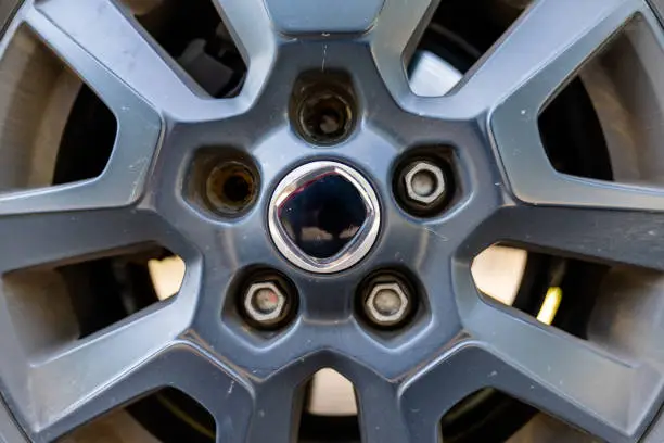 Photo of close up view of the rim and wheel of a car with two broken lug nuts