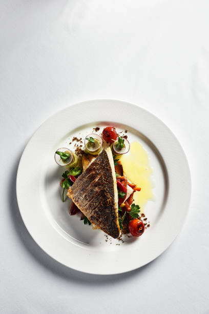 istock Grilled seabass with vegetables top view, close-up, white plate, light background, copy space 1334008493