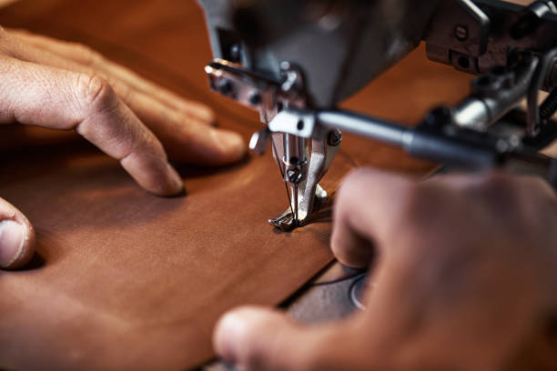 istock Working process of leather craftsman. Tanner or skinner sews leather on a special sewing machine, close up.worker sewing on the sewing machine 1334009653