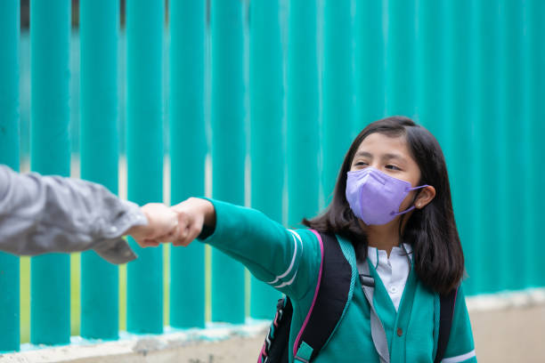 mulher mexicana cumprimentando com distanciamento social na volta à escola após pandemia de coronavírus - regresso às aulas - fotografias e filmes do acervo