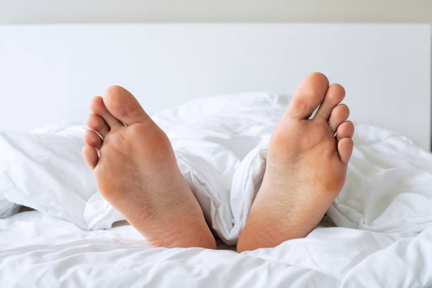istock Male foots in bed under blanket 1334018414