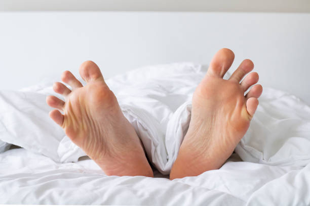 istock Male foots in bed under blanket 1334018422