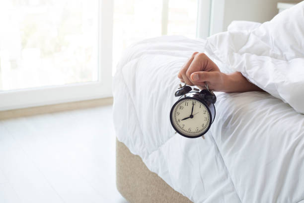 istock Sleeping man holds a mechanical alarm clock in his hands 1334018438