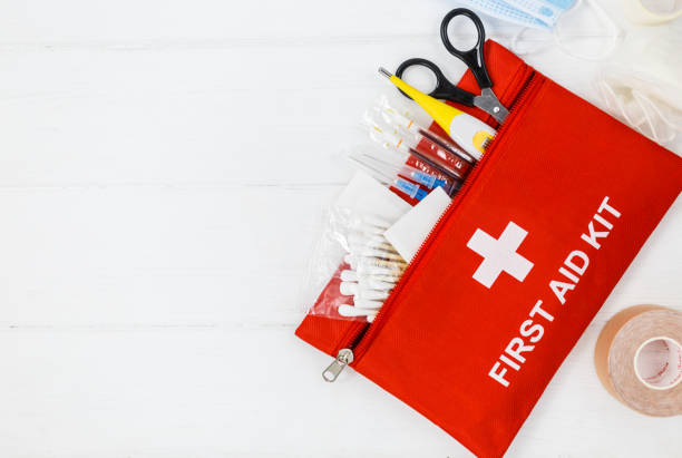 istock First aid kit in red bag on wooden table. Kit with patch, pills, scissors, masks, thermometer, elastic bandages. Top view, close up 1334019366