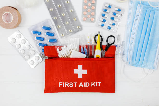 istock First aid kit in red bag on wooden table. Kit with patch, pills, scissors, masks, thermometer, elastic bandages. Top view, close up 1334019367