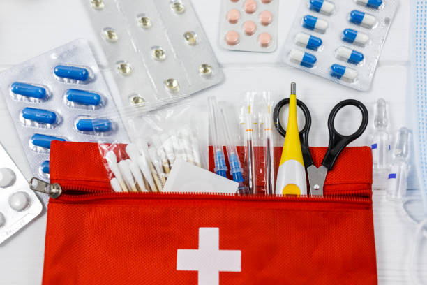 istock First aid kit in red bag on wooden table. Kit with patch, pills, scissors, masks, thermometer, elastic bandages. Top view, close up 1334019376