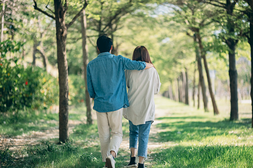 couple in love sitting on tree trunk in arms of each other. guy kisses a girl on the cheek. sunny day in the garden.