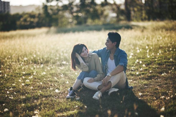 Resting on the green grass, the couple is enjoying the natural surroundings