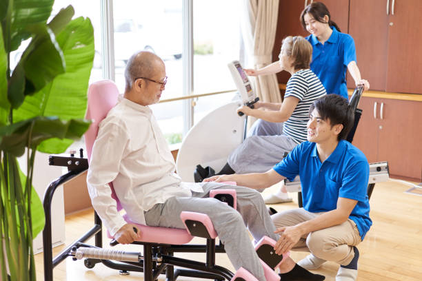 ältere menschen trainieren in der fitnessecke einer langzeitpflegeeinrichtung - physical therapy exercise machine exercising exercise equipment stock-fotos und bilder