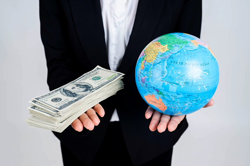 Close up hand holding vintage map of globe Earth world map and money US dollar bills  , business concept