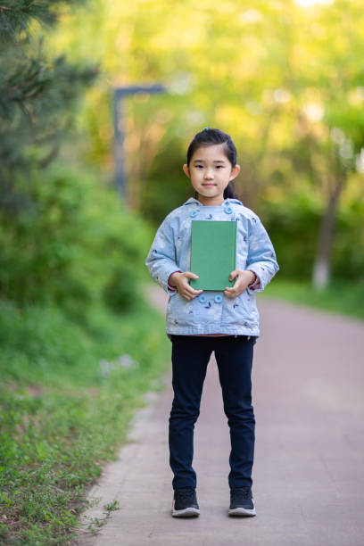 istock Little Girl Holding Book 1334038252