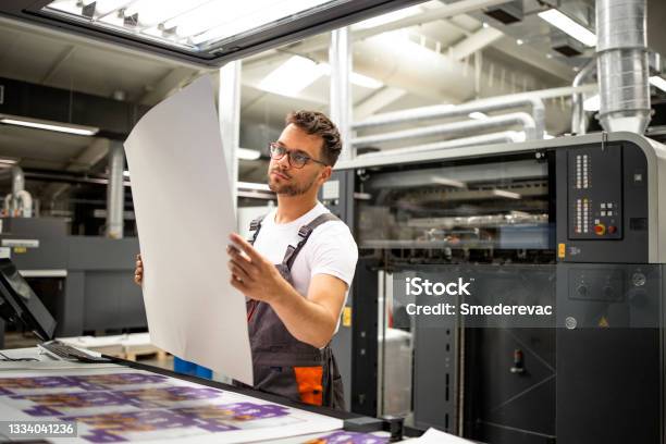 Print Shop Worker Checking Quality Of Imprint And Controlling Printing Process Stock Photo - Download Image Now