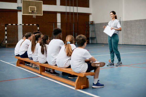 istock Happy physical education teacher talking to her students during a class at elementary school gym. 1334046463