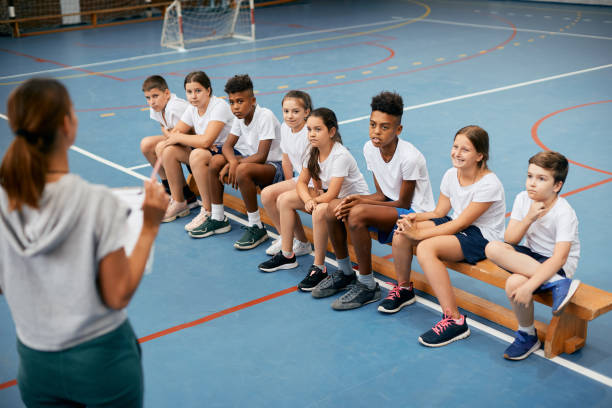 istock Group of elementary students having PE class with female coach at school gym. 1334046536