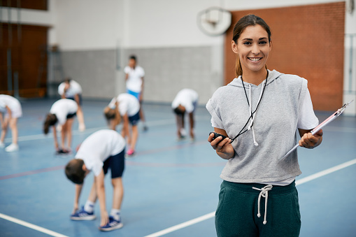 A shot of a young group of teenage students discussing the game with their sports teacher before a basketball match.