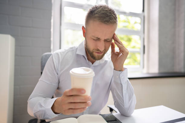 personne tenant une tasse de café ayant mal à la tête - caffeine photos et images de collection