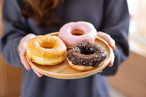 Closeup image of a woman holding a plat of donuts in the kitchen at home