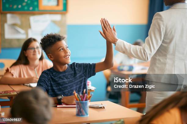 Happy Black Elementary Student And His Teacher Giving High Five During Class At School Stock Photo - Download Image Now