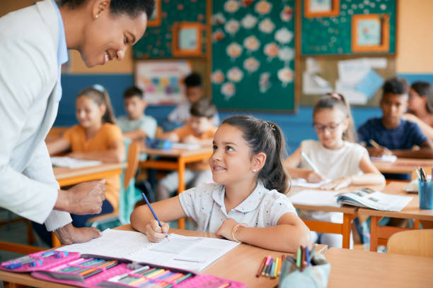 istock Happy schoolgirl talking to a teacher while learning in the classroom. 1334050931