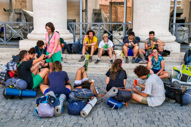 un gran grupo de exploradores disfrutan de un descanso bajo la columnata de bernini en la plaza de san pedro, en el corazón de roma. - youth organization fotografías e imágenes de stock