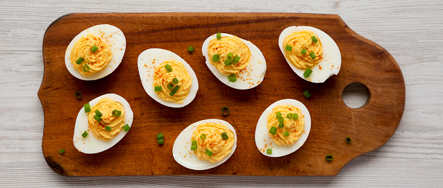 Homemade Deviled Eggs with Chives on a rustic wooden board, view from above. Flat lay, overhead, top view.