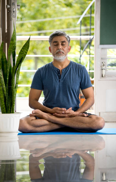 istock Man meditating in lotus position at home 1334062626