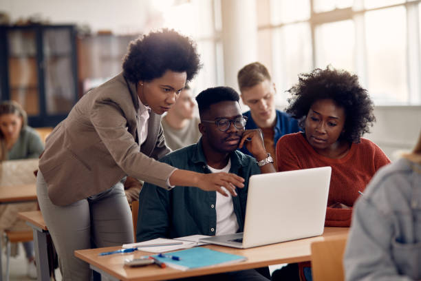 African Americans college students e-leaning with their teacher during a class. African American professor and her students using laptop during lecture in the classroom. university stock pictures, royalty-free photos & images