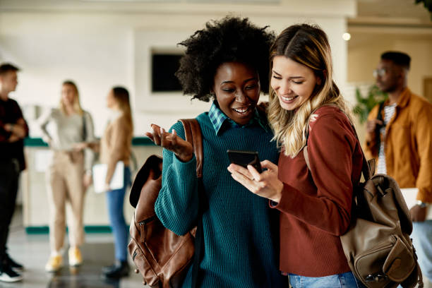 istock Cheerful female students using smart phone in a hallway at the university, 1334064878