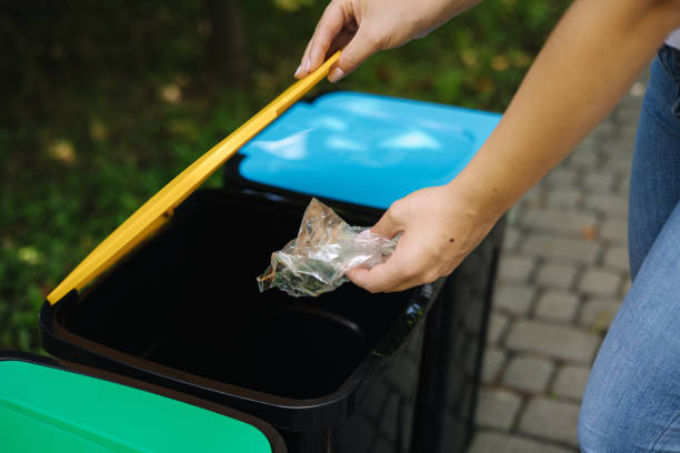 istock Female in the park throwing plastic bag into recycling bin. Different colours on plastic bins. Green, blue and yellow 1334065567