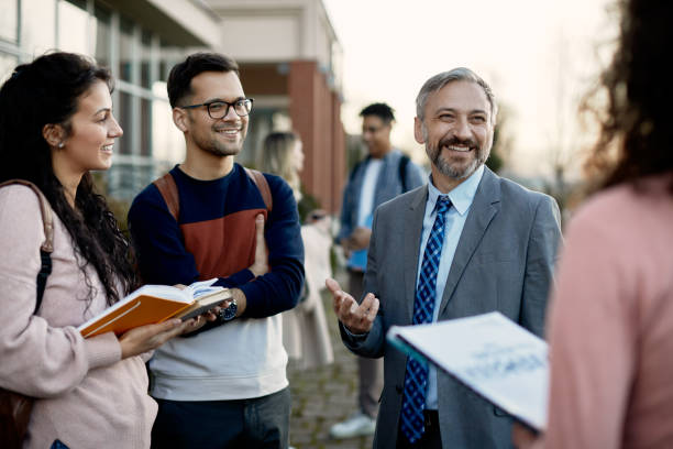 happy mature professor talking to group of college students at campus. - professor bildbanksfoton och bilder