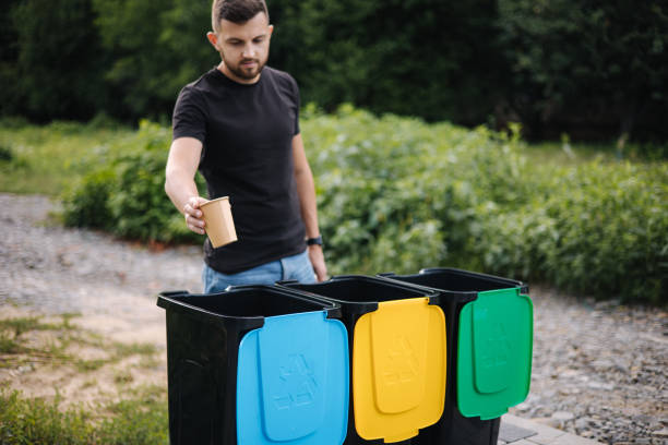 istock Potrait of man throwing empty cardboard cup from cappuccino in recycling bin. Tree recycling bins outdoors 1334065694