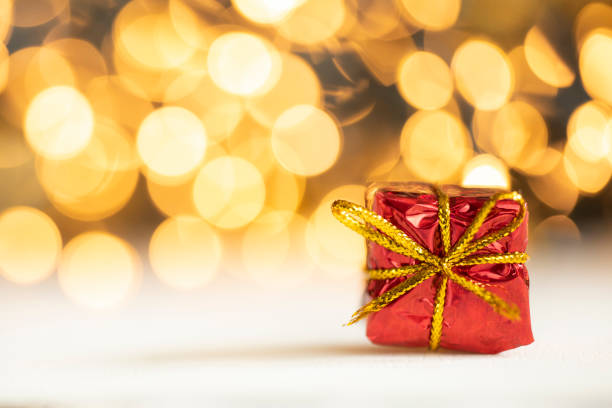christmas present red and silver baubles against bokeh lights gold shiny glitter background with copy space, space for text