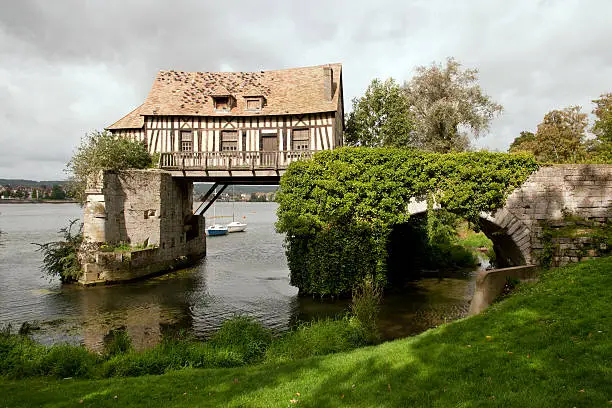 Photo of An old cottage hovering over a lake in a green landscape