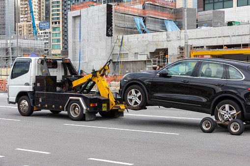 Hong Kong - August 13, 2021 : A tow truck moving a disabled vehicle on a street in Wan Chai, Hong Kong.