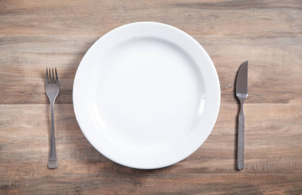 istock Empty plate with fork and knife on wooden table. 1334079616