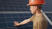 Little boy in a protective helmet at a solar power plant. The concept of children and green energetics. Children for clean energy. Shooting at a solar power plant. Ecological farm. Solar power station