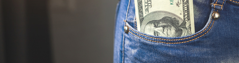 Banner dollars in pocket. Young woman with money in her denim jeans pocket. Concept photo of wealth. Copy space