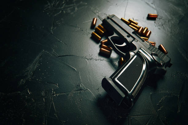 istock Gun with cartridges on dark concrete table. 1334083563