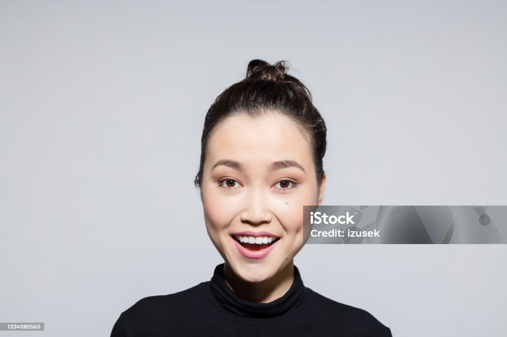Excited asian young woman Headshot of beautiful asian young woman wearing black turtleneck, laughing at camera. Studio shot, grey background. Turtleneck Stock Photo