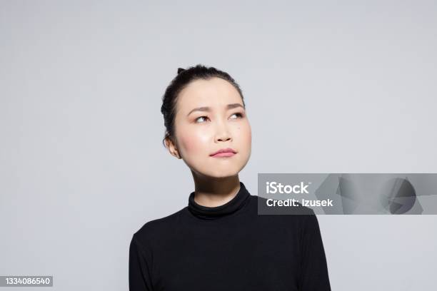 Thoughtful Asian Young Woman Stock Photo - Download Image Now - Headshot, Casual Clothing, Females