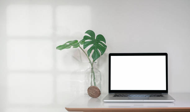 istock Mockup blank screen laptop computer on wooden table in empty room. 1334087857