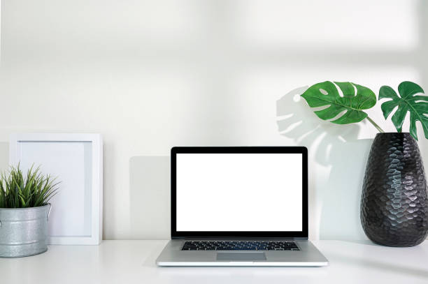 istock Mockup blank screen laptop computer with wooden frame and houseplant on white table. 1334087915