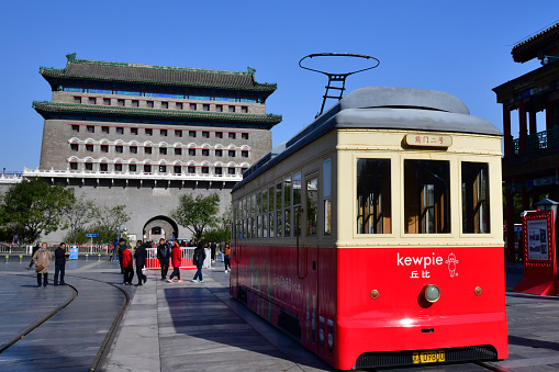 Beijing, China-October 2019; view on the Gate House or Zhengyangmen with in the forefront the colorful historical tram in Qianmen Street, a famous pedestrian streeet for shopping and sightseeing