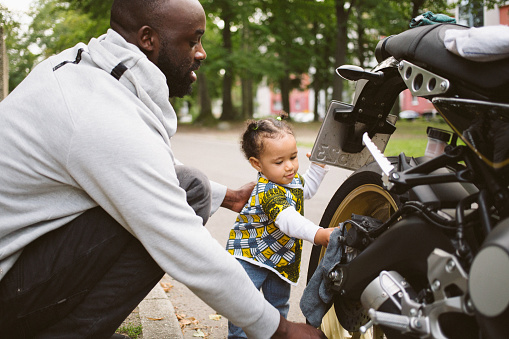 Baby girl helps father while cleaning the motorcycle