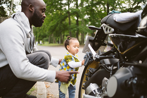 Baby girl helps father while cleaning the motorcycle