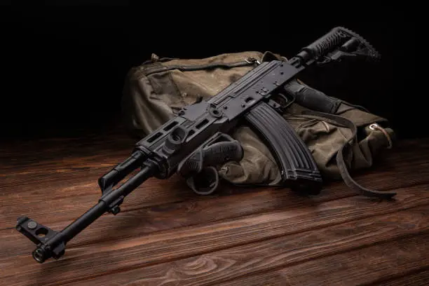 Photo of Soviet carbine in modern body kit. Weapons of Russia and the Soviet Union. Classic Soviet AK machine gun on a wooden background.