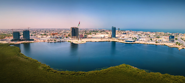 Ras al Khaimah corniche and downtown area of the emirate aerial cityscape landmark skyline rising over the mangroves and the creek water surrounded by seaside and coastline in the United Arab Emirates aerial panoramic view.\nUAE northern emirate