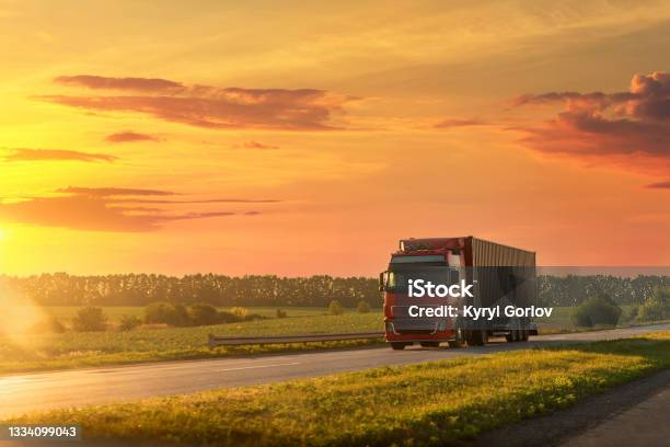 Scenic Front View Big Long Heavy Semitreailer Truck With Sea Shipping Container Driving Highway Dramatic Warm Morning Evening Sunrise Sky Sunset Cargo Transport Industry Background Concept Stock Photo - Download Image Now