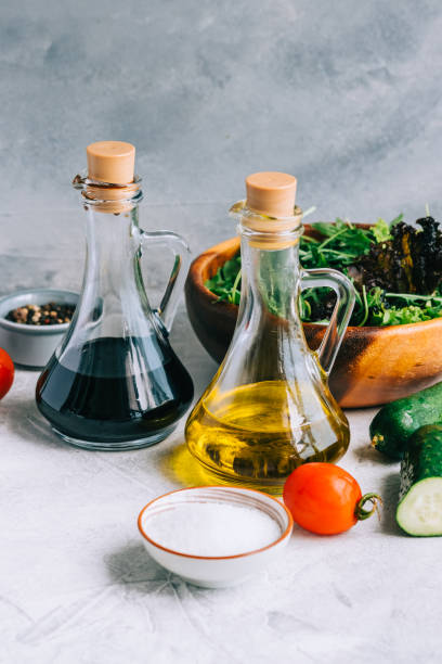 cucinare insalata fresca, ingredienti in tavola con olio d'oliva e aceto balsamico. - vinegar salad dressing balsamic vinegar olive oil foto e immagini stock