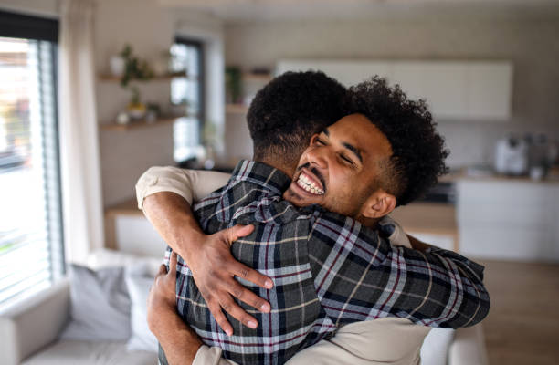 Young happy adult brothers in kitchen indoors at home, hugging. A young happy adult brothers in kitchen indoors at home, hugging. brother stock pictures, royalty-free photos & images
